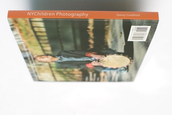 NYChildren Photography Book by Danny Goldfield features a young boy playing a Djembe drum  on the back cover with his eyes closed, lost in his music.