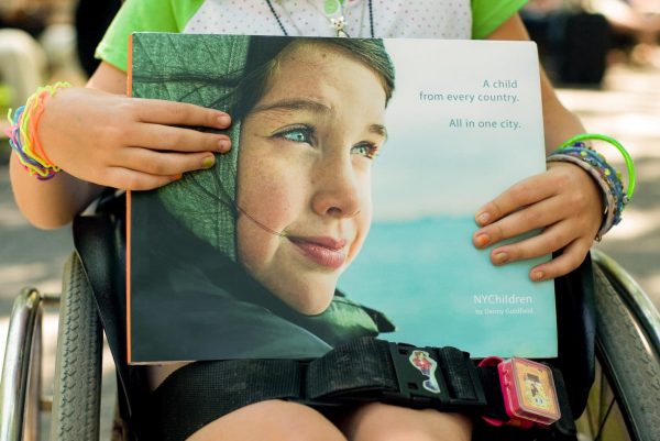 NYChildren Photography Book by Danny Goldfield in the hands of a girl with multi colored bracelettes and nail polish.
